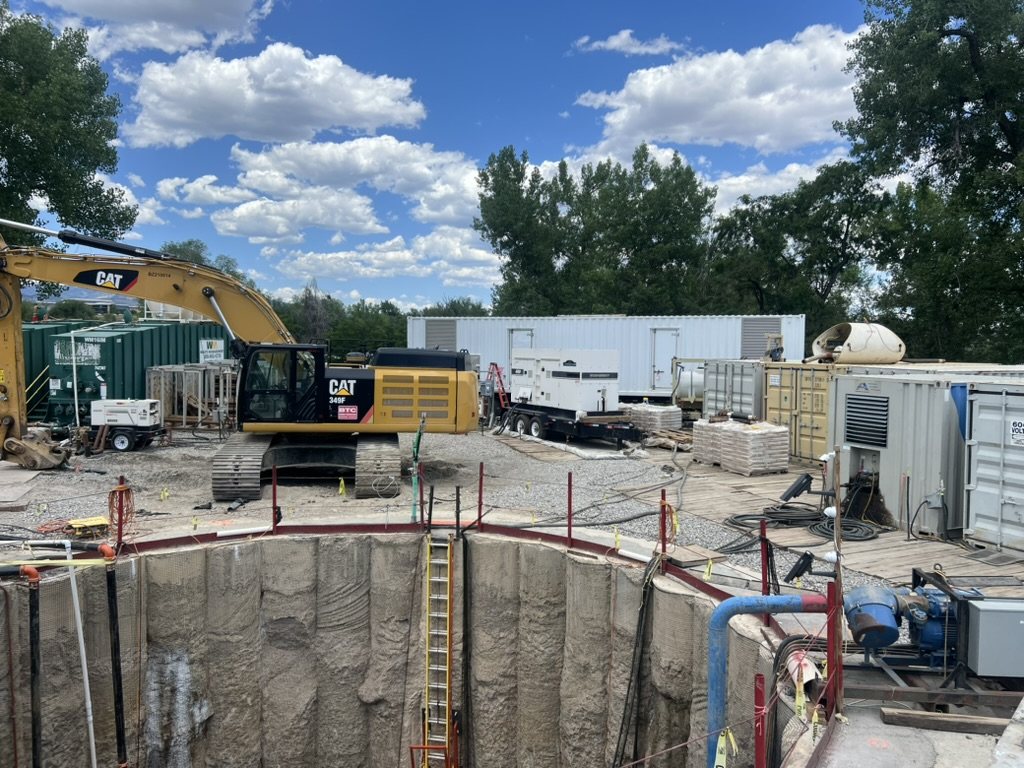 Large excavation site with boring equipment and pipe installation work
